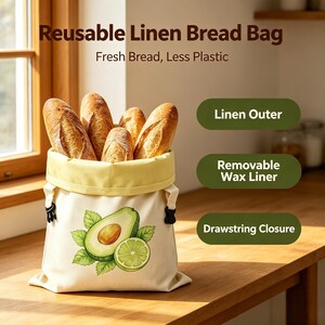 May include: A reusable linen bread bag with a drawstring closure, a removable wax liner, and an avocado and lime graphic. The bag contains several loaves of bread. Text on the image reads: Reusable Linen Bread Bag, Fresh Bread, Less Plastic.
