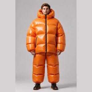 May include: A bright orange puffer jacket and matching puffer trousers set. The jacket features a high collar, a hood, and a black front zip. The trousers have a high-waisted, quilted design. Both pieces are made of a shiny, water-resistant material.
