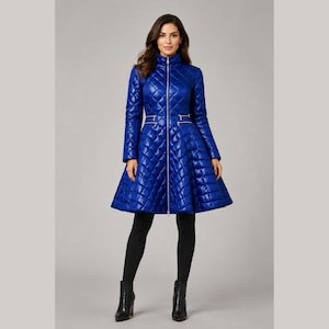 Può includere: Un cappotto trapuntato blu reale vivace con collo alto, cerniera frontale argentata a tutta lunghezza e due tasche orizzontali con cerniera in vita. Il capo presenta una silhouette svasata a trapezio, maniche lunghe e una finitura lucida.