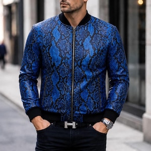 Könnte beinhalten: Eine blau-schwarze Bomberjacke mit Schlangenledermuster, durchgehendem Frontreißverschluss, schwarzem Rippstrickkragen und schwarzen Rippstrickbündchen. Die Jacke hat einen strukturierten Reptilien-Print, lange Ärmel und zwei seitliche Reißverschlusstaschen.