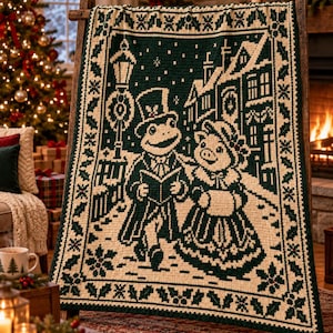 May include: A rectangular crochet blanket featuring a dark green and cream colour scheme. The design depicts a frog and a pig dressed in Victorian-style clothing, singing carols on a street with a lamppost and buildings, framed by a holly leaf border.