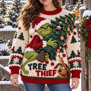Könnte beinhalten: Ein cremefarbener Häkelpullover mit einem grünen Charakter in roter Weihnachtsmannmütze, der einen großen geschmückten Weihnachtsbaum hält. Der Pullover hat rote Rippbündchen, kleine grüne Baummuster und den Schriftzug "TREE THIEF" in roter Farbe.