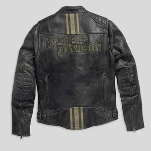 Può includere: Una giacca in pelle nera con finitura invecchiata, toppe trapuntate sui gomiti e polsini con zip. Il retro presenta la scritta Harley-Davidson Motorcycles ricamata in verde oliva con strisce verticali color oliva e beige sopra e sotto.
