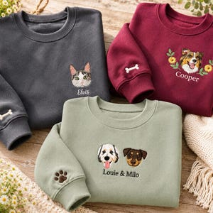 Può includere: Tre felpe girocollo in grigio antracite, bordeaux e verde salvia. Ognuna presenta ritratti di animali ricamati e nomi personalizzati, tra cui Elvis, Cooper e Louie & Milo. Le maniche mostrano dettagli ricamati a forma di osso o zampa.
