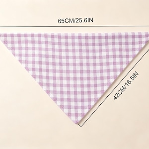 May include: A triangular bandana featuring a light purple and white gingham check pattern. The fabric accessory measures 25.6 inches along the top edge and 16.5 inches along the side edge as indicated by the printed dimension lines.