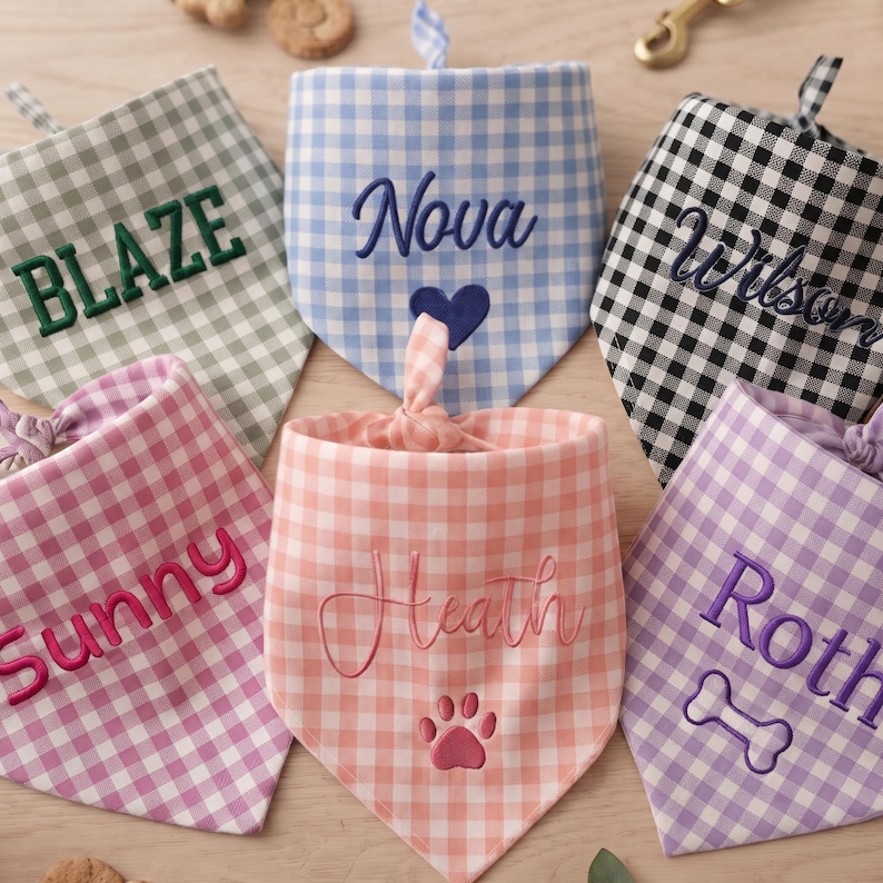 May include: A collection of six triangular pet bandanas featuring gingham patterns in sage green, light blue, black, pink, peach, and lavender. Each bandana is embroidered with a name and a symbol, including Blaze, Nova, Wilson, Sunny, Heath, and Roth.