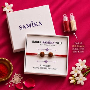 May include: A Rakhi bracelet with two brown rudraksha beads and silver accents on a red thread, presented in a white box labeled RAKHI SAMIKA WALI 925 SILVER HAPPY RAKSHA BANDHAN, accompanied by two small vials of red and white powder.