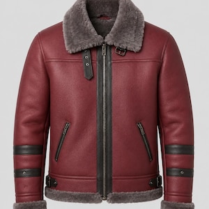 May include: A deep burgundy leather jacket featuring a thick grey shearling collar and hem. The jacket includes a central zipper, two slanted zippered pockets, black leather accents on the sleeves, and adjustable buckle straps at the waist.