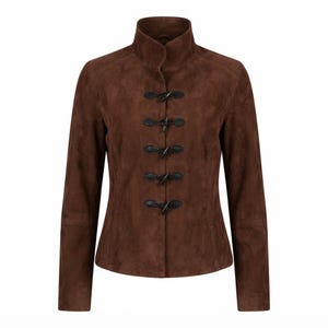 May include: A dark brown suede jacket featuring a high collar and a front closure with five black toggle fasteners. The jacket has long sleeves and a structured fit, showcasing a soft, matte texture throughout the entire garment surface.