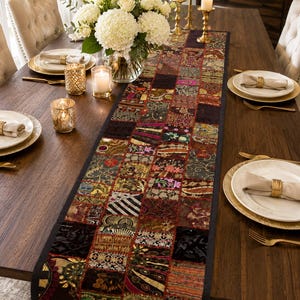 May include: A long rectangular table runner featuring a patchwork design of various fabric squares in dark tones of burgundy, gold, black, and green. The runner displays intricate embroidered patterns, metallic threads, and sequins throughout the surface.