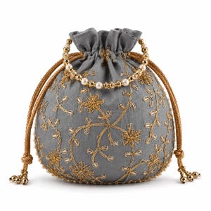 May include: A grey drawstring pouch bag featuring gold metallic floral embroidery and clear bead accents. The bag includes a top handle made of gold-toned beads and pearls, with two gold braided drawstrings ending in small metallic bead tassels.