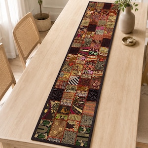 May include: A long rectangular table runner featuring a patchwork design of various fabric squares in dark tones of red, gold, green, and black. The runner is decorated with intricate embroidery, metallic threads, and sequins throughout the surface.