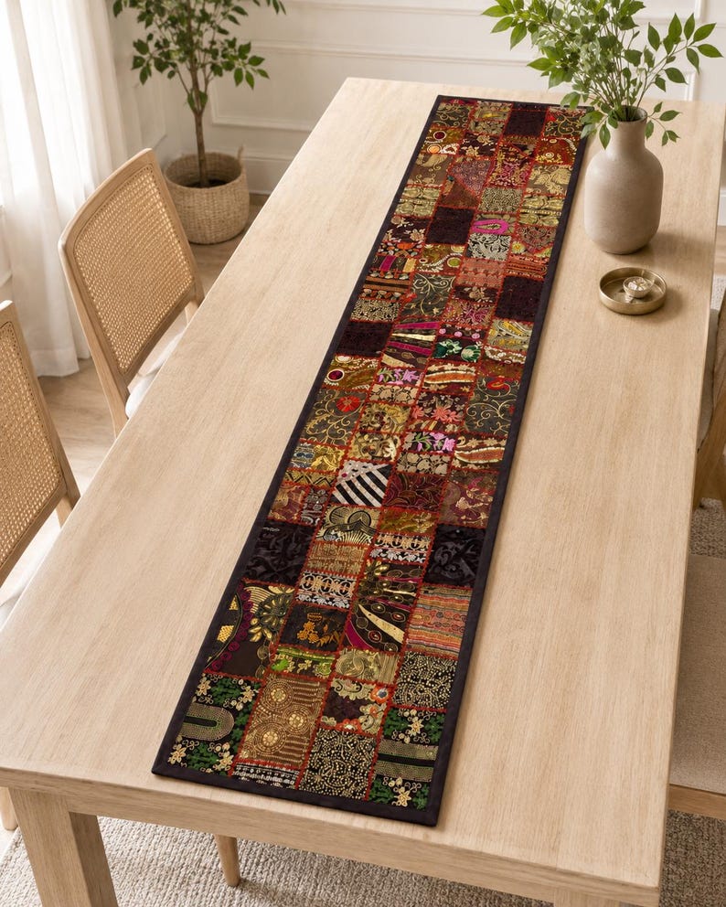 May include: A long rectangular table runner featuring a patchwork design of various fabric squares in dark tones of red, gold, green, and black. The runner is decorated with intricate embroidery, metallic threads, and sequins throughout the surface.