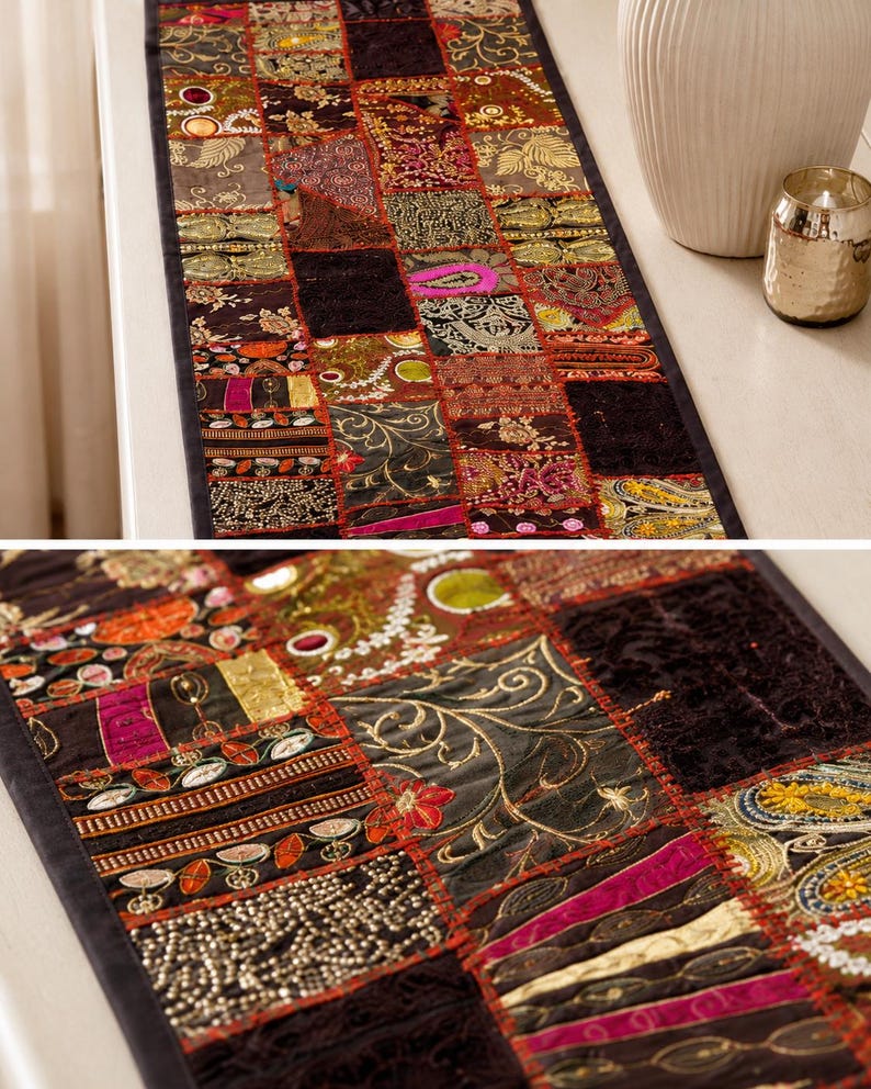 May include: A rectangular table runner featuring a patchwork design of various dark-toned fabric squares. The runner includes intricate gold embroidery, metallic thread accents, sequins, and floral patterns in shades of burgundy, black, and gold.