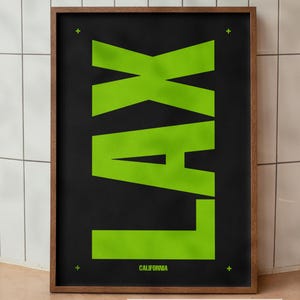 Puede incluir: Un póster vertical enmarcado que presenta el texto LAX en letras grandes y llamativas de color verde lima sobre un fondo negro sólido. La palabra CALIFORNIA aparece en un texto más pequeño de color verde lima en la parte inferior.