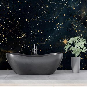 May include: A dark gray oval freestanding bathtub with a chrome faucet, positioned in front of a wall mural featuring a deep blue night sky filled with gold constellations, stars, and nebulae, alongside a green potted plant in a gray pot.