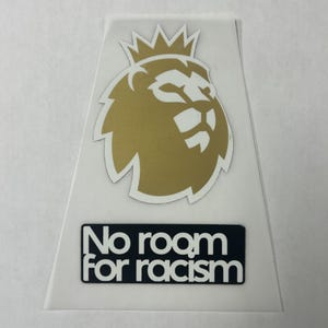 May include: A trapezoidal sticker featuring a gold lion head icon with a crown on top, positioned above a rectangular black label with the white text "No room for racism" printed in a bold, sans-serif font against a plain white background.