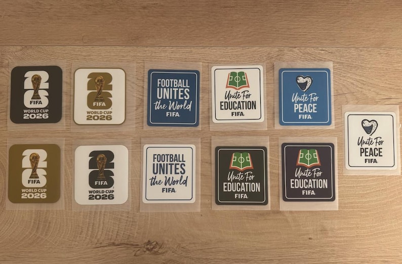 Peut inclure: Une collection de onze autocollants carr&eacute;s pr&eacute;sentant les logos de la Coupe du Monde de la FIFA 2026, Football Unites the World, Unite for Education et Unite for Peace dans des coloris vari&eacute;s incluant le noir, le blanc, l'or, le bleu et le vert.