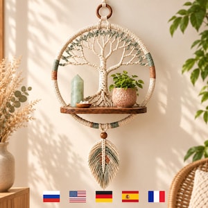May include: A circular macrame wall hanging featuring a tree design in cream, sage green, and brown cord. It includes a dark wooden shelf holding a green crystal point and a small potted plant. A single macrame feather hangs from the bottom.