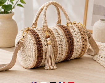 May include: A cylindrical crochet handbag featuring alternating horizontal stripes in cream, beige, and dark brown. The bag includes two top handles, a detachable shoulder strap with gold-tone hardware, and a decorative tassel charm with wooden beads.