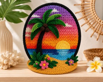 May include: A circular crochet wall hanging featuring a tropical beach scene with a black palm tree, a yellow sun, and a gradient sky transitioning from purple to orange. The base includes green foliage and pink flowers, all framed by a thick black border.