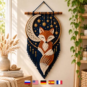 Può includere: Un arazzo in macramè con una figura centrale di volpe arancione e crema appoggiata a una grande mezzaluna color crema. Il design è posto su uno sfondo circolare blu scuro decorato con stelle dorate e rifinito con lunghe frange blu.