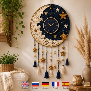 Puede incluir: Un reloj de pared circular con un centro azul oscuro y manecillas doradas, rodeado por una media luna de ganchillo en color crema sobre un fondo de cielo nocturno azul oscuro. La pieza está decorada con estrellas de ganchillo y borlas colgantes.