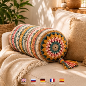 May include: A cylindrical bolster pillow featuring a multi-colored crochet pattern with concentric circles in shades of mustard yellow, teal, pink, and cream. The pillow ends in a decorative tassel made of matching yarn strands in various colors.