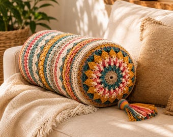 May include: A cylindrical bolster pillow featuring a multi-colored crochet pattern with concentric circles in shades of mustard yellow, teal, pink, and cream. The pillow ends in a decorative tassel made of matching yarn strands in various colors.