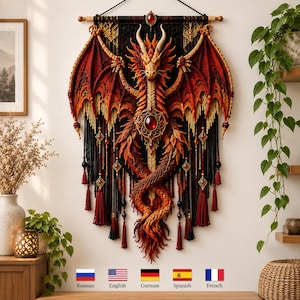 Könnte beinhalten: Ein Wandbehang mit einem detaillierten roten und orangen Drachen mit großen Flügeln, gefertigt aus komplexen Faserstrukturen. Der Drache ist auf einem schwarzen Hintergrund zentriert und mit hängenden Quasten, Perlen und einem roten Edelstein verziert.