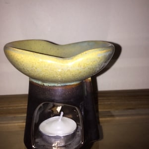 Könnte beinhalten: Ein Keramik-Ölbrenner mit gelber und brauner Glasur. Der Brenner hat eine kleine Öffnung für ein Teelicht. Das Teelicht ist im Lieferumfang enthalten.