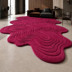 May include: A large, irregular, magenta-colored area rug featuring a textured, wavy, topographical pattern of raised lines that create a fluid, organic shape across the floor, covering a significant portion of the room's light-colored tile surface.