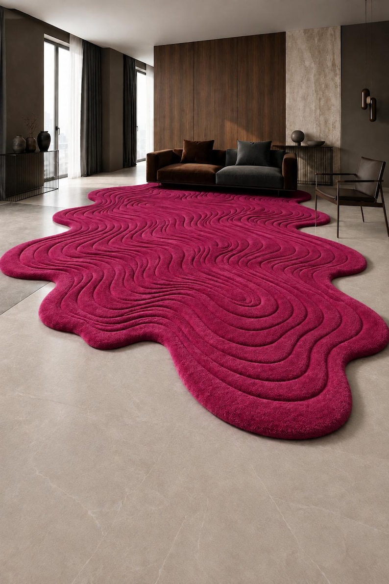 May include: A large, irregular, magenta-colored area rug featuring a textured, wavy, topographical pattern of raised lines that create a fluid, organic shape across the floor, covering a significant portion of the room's light-colored tile surface.