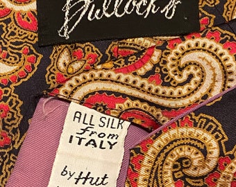 Pode incluir: Uma gravata de seda com padrão paisley preto e branco com uma etiqueta branca que diz "All Silk From Italy by Hut WFL 857". A gravata também tem uma etiqueta preta que diz "Bullock's".