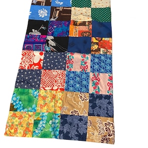 May include: A patchwork quilt made of various colorful fabrics with floral and geometric patterns. The quilt is made up of 16 squares, each with a different design.