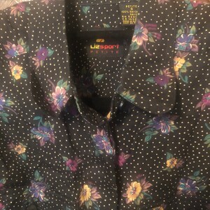 May include: A black button-down shirt with a floral print and white polka dots. The shirt has a LizSport Petite label.