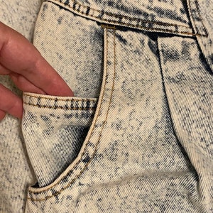 K&ouml;nnte beinhalten: Nahaufnahme einer hellblauen Jeans-Tasche an einer S&auml;ure-Wasch-Jeans. Die Tasche hat einen hellbraunen Stich an den R&auml;ndern.