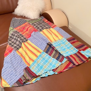 May include: A colorful patchwork skirt with a variety of plaid and striped patterns in shades of blue, red, yellow, and brown.