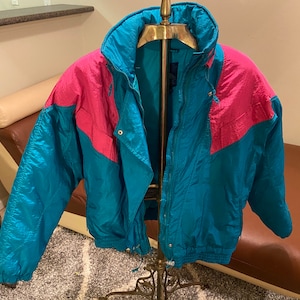 May include: A teal and pink vintage puffer jacket with a zipper closure and a drawstring waist.