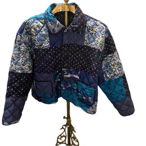 May include: A blue quilted jacket with a patchwork design featuring floral and polka dot patterns. The jacket has a button closure and a collar.
