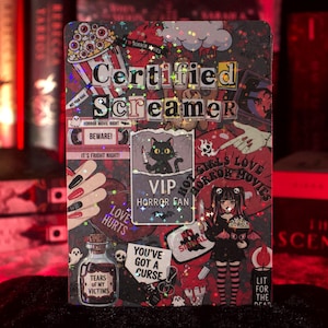 May include: A rectangular holographic sticker featuring the text Certified Screamer, VIP Horror Fan, Love Hurts, You've Got A Curse, and Tears Of My Victims. The design includes a black cat with a knife, a person holding popcorn, and horror icons.