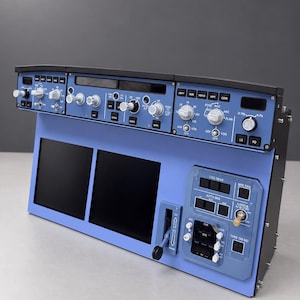 Puede incluir: Un panel de control de cabina de avión azul con dos pantallas negras, múltiples perillas giratorias, botones y una palanca vertical. El panel incluye etiquetas como LDG GEAR, AUTO BRK, BRK FAN y TERR ON ND, con un marco de color negro.