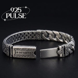 May include: A silver bracelet featuring a thick curb chain design with intricate floral engravings and a rectangular box clasp. The clasp displays the text "FOREVER" in a gothic font. The text "925 PULSE" is visible in the upper left corner.
