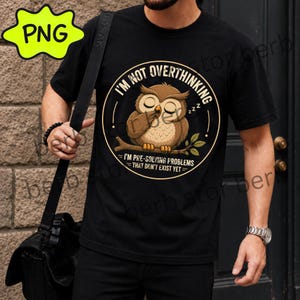 Puede incluir: Una camiseta negra con un gráfico circular de un búho marrón posado en una rama con los ojos cerrados. El texto dice: I'M NOT OVERTHINKING, I'M PRE-SOLVING PROBLEMS THAT DON'T EXIST YET. El diseño incluye pequeños símbolos zzz cerca del búho.
