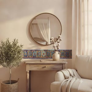 Peut inclure: Un miroir rond avec un cadre métallique fin est suspendu au-dessus d'une console en bois. Une bande horizontale de carreaux colorés à motifs longe le mur derrière la table. Un vase en céramique contenant des tiges de coton est posé dessus.