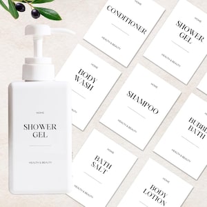 Può includere: Un flacone rettangolare in plastica bianca con erogatore a pompa etichettato SHOWER GEL, accompagnato da diverse etichette rettangolari bianche con testo nero tra cui CONDITIONER, SHOWER GEL, HAND WASH, BODY WASH, SHAMPOO, BUBBLE BATH, BATH SALT e BODY LOTION.