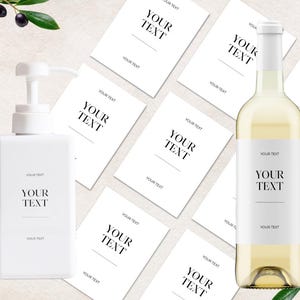 Pode incluir: Um frasco retangular branco com bomba e uma garrafa de vinho de vidro transparente, ambos com etiquetas brancas com o texto preto YOUR TEXT. Várias etiquetas retangulares brancas adicionais com o mesmo texto estão dispostas no fundo.