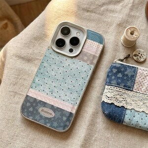 May include: A smartphone case featuring a patchwork design of light blue polka dot fabric, a pink strip, and a dark blue star-patterned fabric with a small oval patch labeled Bonne. Next to it is a small denim pouch with lace trim.