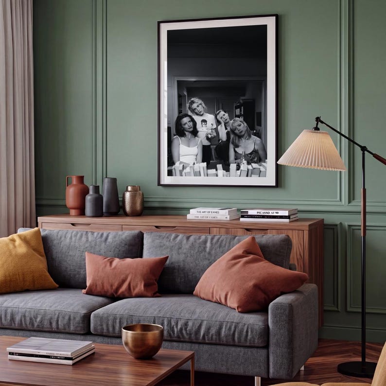 Op de afbeelding: Een ingelijste zwart-witfoto van vier personen in een kamer, opgehangen aan een saliegroene muur boven een houten dressoir. De afdruk toont een groep mensen in een informele setting, vastgelegd in contrastrijke monochrome tinten.