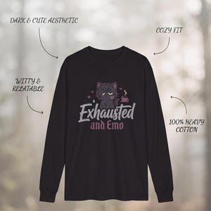May include: A black long-sleeve shirt featuring a graphic of a tired cat with a coffee cup and the text "Exhausted and Emo". The image includes labels "THE EXHAUSTED & EMO LONG SLEEVE", "DARK & CUTE AESTHETIC", "COZY FIT", "WITTY & RELATABLE", and "100% HEAVY COTTON".